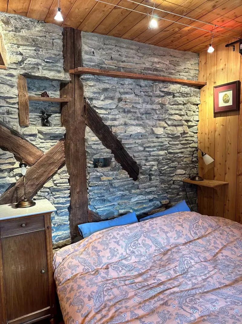 Chambre avec lit double et mur en pierre
