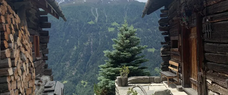 Balcon d'un vieux chalet en bois avec bûches et vue sur la vallée