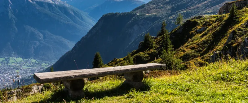 Banc en bois face à la vallée et aux montagnes du Valais
