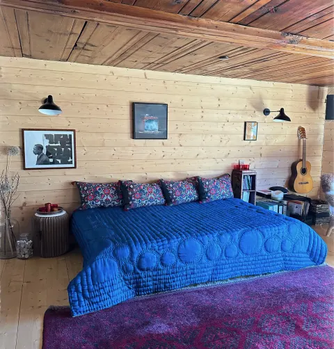Chambre rénovée avec lambris clair et couvre-lit bleu