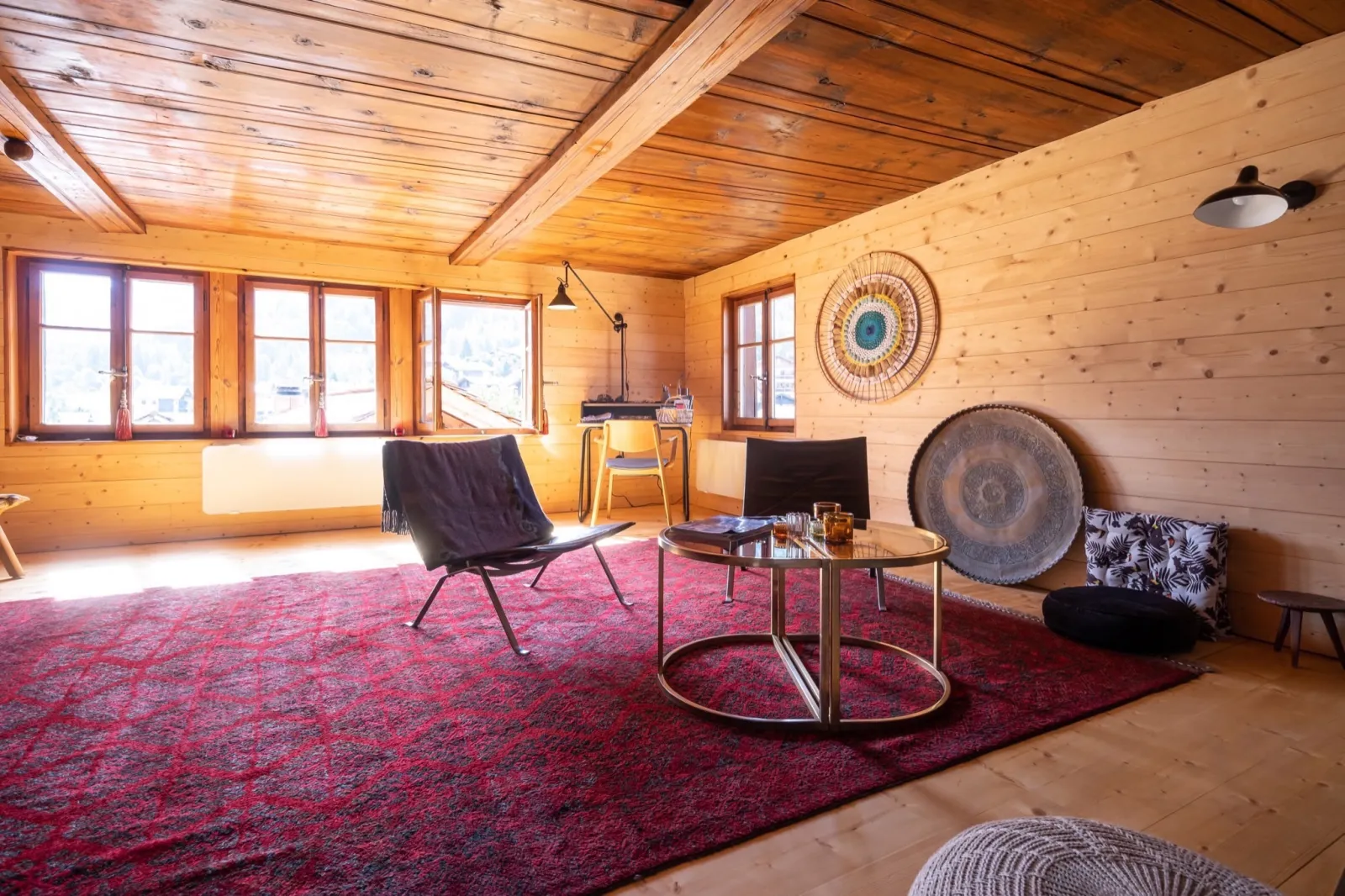 Séjour de chalet décoré : tapis rouge, fauteuil design et table en laiton