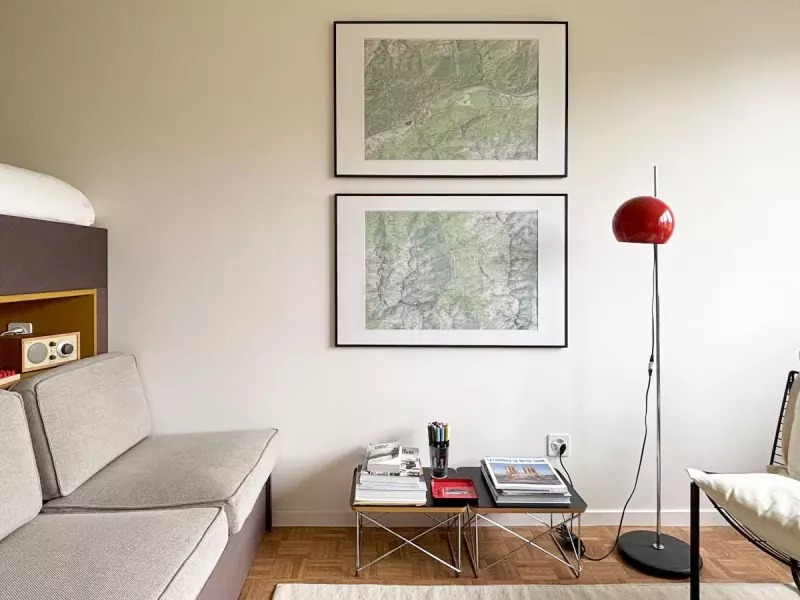 Coin salon avec banquette, lampe rouge et cartes anciennes