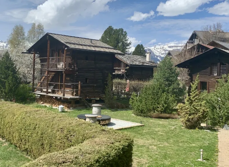 Vieux chalets en bois et jardin au cœur d'un village de montagne